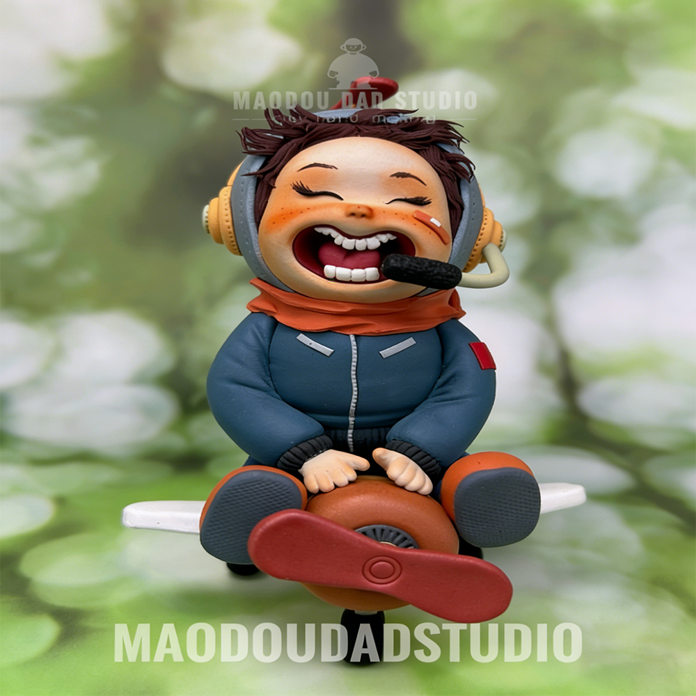 Little Pilot handmade clay figurine – front view on tiny propeller plane with orange scarf and helmet